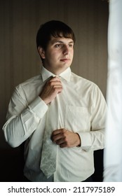 Penza, Russian Federation - August 6, 2016: A man in a white shirt. The groom buttons his shirt. A man in a white tie.