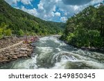 People along the Ocoee river on the rocks to whitewater kayak and raft at the Ocoee whitewater center in Tennessee on a sunny day in late summertime