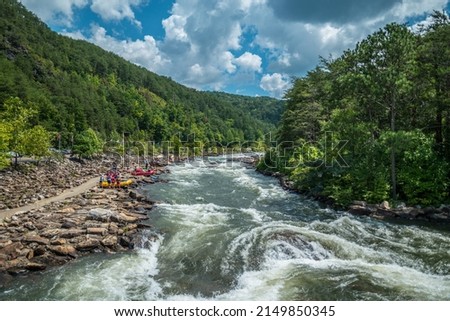 People along the Ocoee river on the rocks to whitewater kayak and raft at the Ocoee whitewater center in Tennessee on a sunny day in late summertime