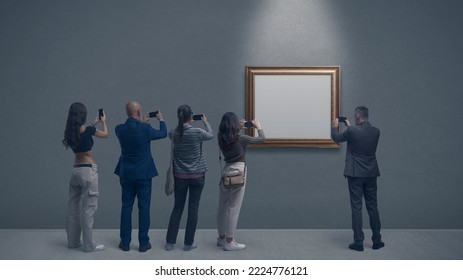 People at the art gallery, they are taking pictures of a painting using their smartphones - Shutterstock ID 2224776121