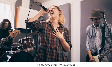 People, band and music practice with singer, microphone and electric guitar for concert rehearsal at home. Musician group, vocal training and recording song, track and audio with team work in garage - Powered by Shutterstock