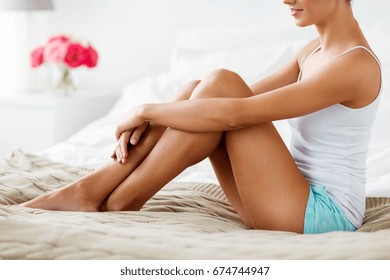 People, Beauty, Depilation, Epilation And Bodycare Concept - Beautiful Woman With Bare Legs Sitting On Bed At Home Bedroom