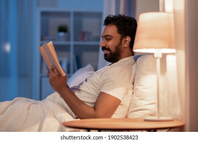 People, Bedtime And Rest Concept - Happy Smiling Indian Man Reading Book In Bed At Home At Night