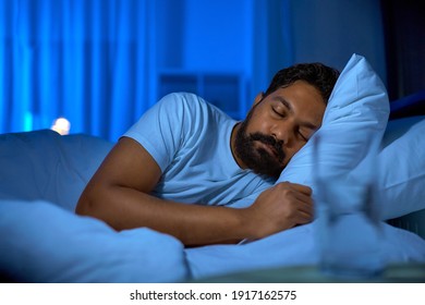 people, bedtime and rest concept - indian man sleeping in bed at home at night - Powered by Shutterstock