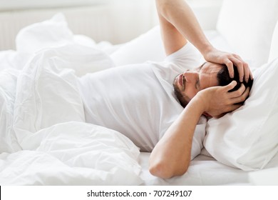 People, Bedtime And Rest Concept - Man Lying In Bed At Home Suffering From Headache Or Hangover