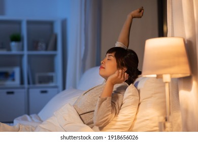 People, Bedtime And Rest Concept - Sleepy Asian Woman Stretching In Bed At Night