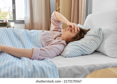 people, bedtime and rest concept - sleepy teenage girl lying in bed at home in morning