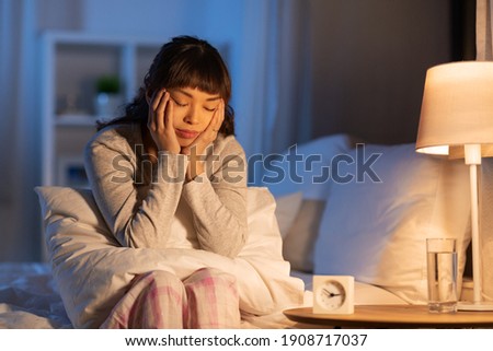 people, bedtime and rest concept - stressed asian woman having headache in bed at night