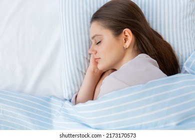 people, bedtime and rest concept - teenage girl sleeping in bed at home in morning