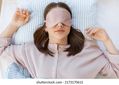people, bedtime and rest concept - teenage girl sleeping in eye mask in bed at home in morning