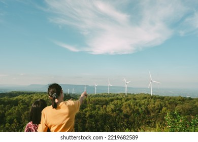People behind concpet, mother and children looking the windmill on blue sky of hills background, kid and mom pointing wind turbine on hill of mountain of beautiful landscape for travel on vacation  - Shutterstock ID 2219682589
