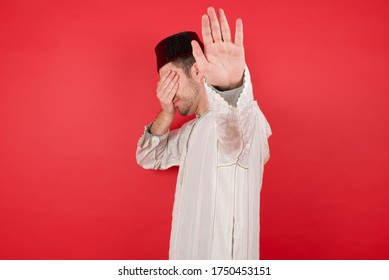People, Body Language. Young Caucasian Muslim Man Covers Eyes With Palm And Doing Stop Gesture, Tries To Hide From Everybody. Don't Look At Me, I Don't Want To See, Feels Ashamed Or Scared.