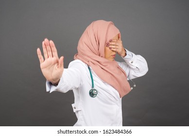 People, Body Language. Young European Doctor Muslim Woman Covers Eyes With Palm And Doing Stop Gesture, Tries To Hide From Everybody. Don't Look At Me, I Don't Want To See, Feels Ashamed Or Scared.
