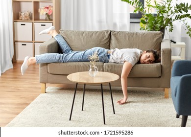 people, boredom and depression concept - bored or lazy young woman lying on sofa at home
