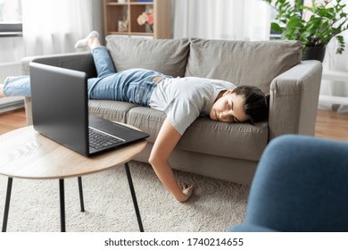 people, boredom and depression concept - bored or lazy young woman with laptop computer lying on sofa at home