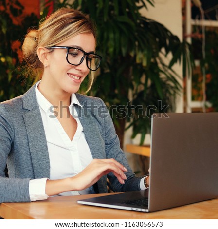 People and business concept: A young attractive business woman sitting in a cafe with a laptop