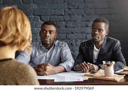 People, business, human resources and recruitment concept. Unrecognizable female candidate with short hair is interviewed by two attractive businessmen during job interview for accountant position
