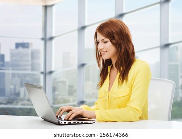 People, Business And Technology Concept - Smiling Young Woman With Laptop Computer Sitting At Table Over Office Window Background