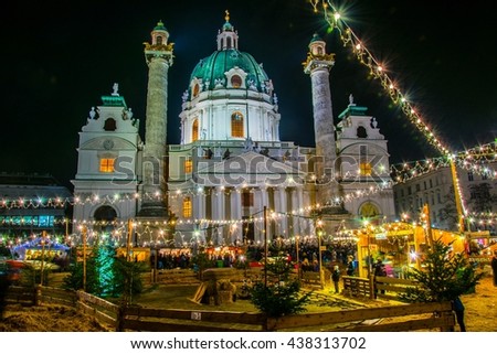 People are buying various articles, admire small enclosure with goats and sheep and play with hay during a christmas market taking place in front of the karlskirche in vienna