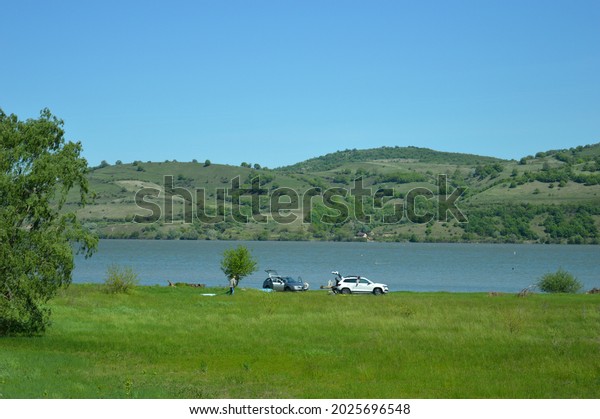 people with cars on a\
picnic by the river