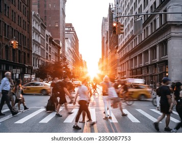 People, cars, taxis and bikes in the busy intersection of 5th Avenue and 23rd Street in New York City with summer sunset shining between the background buildings - Powered by Shutterstock