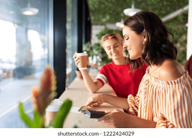 People, Cash Payment And Finances Concept - Female Friends Paying By Credit Card For Coffee At Cafe