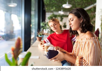 People, Cash Payment And Finances Concept - Female Friends Paying In Dollar Money For Coffee At Cafe