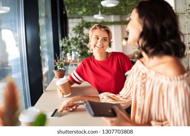 People, Cash Payment And Finances Concept - Female Friends Paying By Credit Card For Coffee At Cafe