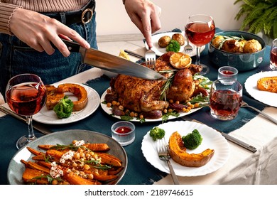 People Celebrating Thanksgiving Day. Woman Cutting Meat For Family And Friends On Table. Traditional Holiday Stuffed Baked Chicken Dinner And Vegetable. Family Party Or Gathering.