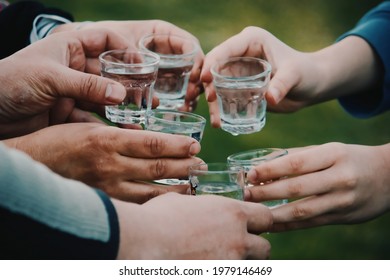 people celebrating and toasting with shots of alcohol vodka outdoors