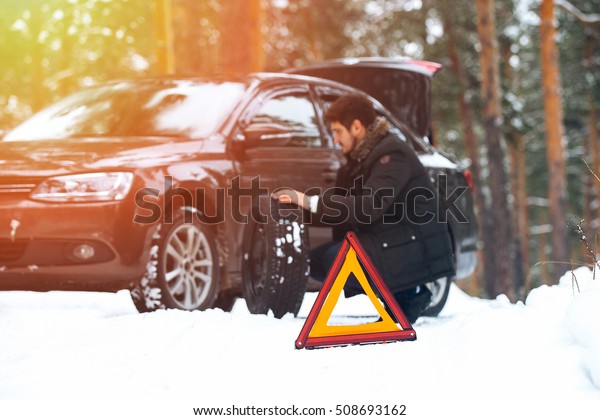 People change a wheel after a broken car on road\
in winter forest
