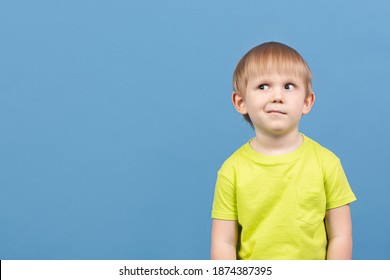 People Child Looks Away, Face Expresses Doubt, Disbelief, Curiosity, Dilemma, Guesswork, Imagination, Planning And Mischief. Cunning Kid Skeptic Suspects Something. Studio Shot With Copy Space.