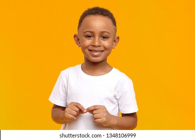 People, childhood, school age and lifestyle concept. Horizontal studio image of handsome adorable African American schoolboy dressed in white t-shirt, looking at camera with broad happy smile - Powered by Shutterstock