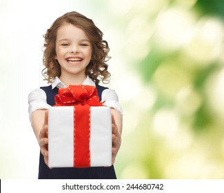 people, childhood, summer and holidays concept - happy smiling girl with gift box over green background
