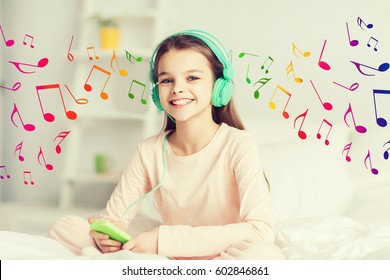concepto de gente, niños, descanso y tecnología - sonriente feliz, muchacha despierta con smartphone y auriculares en la cama escuchando música en casa