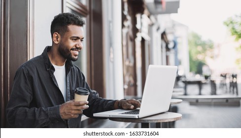 People city lifestyle young man sitting at cafe using laptop computer typing keyboard online outside banner panorama. Modern lifestyle, connection, business, online studying, freelance work concept