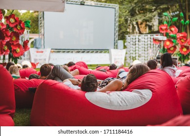 people at city public park watching movie at open air cinema - Powered by Shutterstock