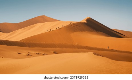 People climbing sand dunes in Sossusvlei area, Namib-Naukluft National Park, Namibia enjoying from their summit stunning view of the world’s oldest desert, the Namib Desert. - Powered by Shutterstock