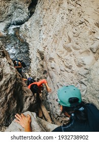 People climbing using some help with friends meanwhile climbing a waterfall