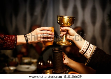 people clink by cups on a medieval feast.