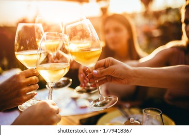 People clinking glasses with wine on the summer terrace of cafe or restaurant