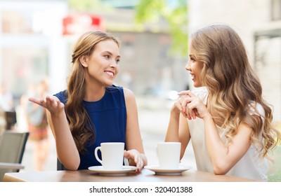 People, Communication And Friendship Concept - Smiling Young Women Drinking Coffee Or Tea And Talking At Outdoor Cafe