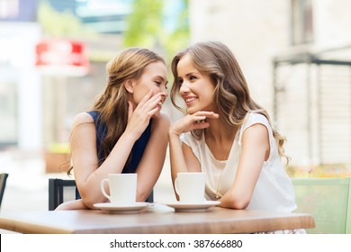 people, communication and friendship concept - smiling young women drinking coffee or tea and gossiping at outdoor cafe