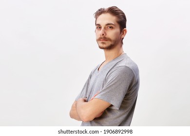 People Concept - Bearded Face Man Cross Arms. Friendly Young Man In Gray Shirt Look In To The Camera Over Grey Background. Copy Space