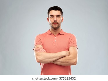 people concept - serious young man in polo t-shirt with crossed arms over gray background - Powered by Shutterstock