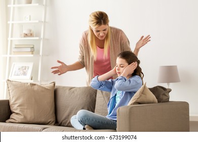 people, conflict and family concept - girl covering ears to not hear angry mother at home