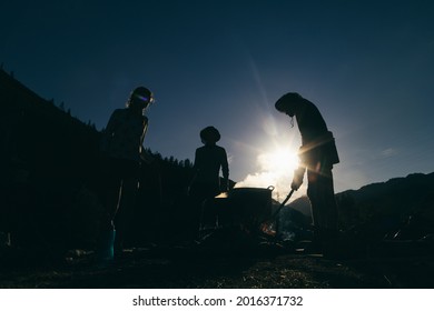 People cook on a fire. Silhouette photo.  Smoke from the fire. Bright sun in the sky. - Shutterstock ID 2016371732