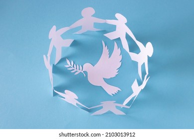 People Cut Out Of Paper On A Blue Background Protect The Dove Of Peace.The Concept Of The World Peace Day.