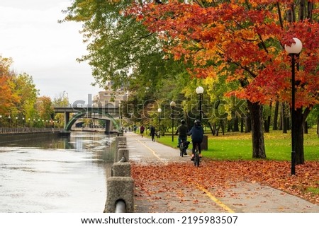 People cycling and walking in Rideau Canal Eastern Pathway. Autumn scenery in Ottawa, Ontario, Canada.