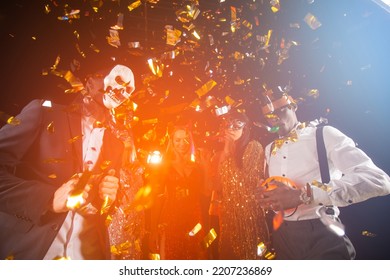 People Dance At Halloween Party With Champagne Glasses. Friends In The Costumes In Nightclub